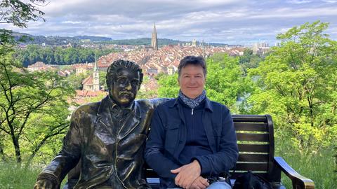 Dieter Voss (rechts) sitzt auf einer Bank neben einer bronzenen Figur von Albert Einstein