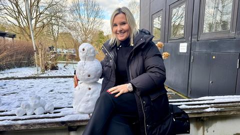 Britta Wiegand mit einem kleinen Schneemann auf einer Bank vor dem hr4-Studio