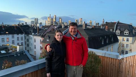 Dieter Voss mit Schornsteinfegerin Xenia Schuhmann (links) auf dem Dach vor der Skyline Frankfurts