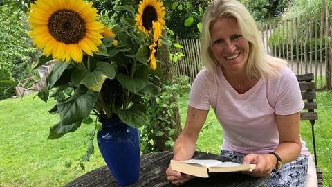 Britta Lohmann mit einem Buch unter dem Apfelbaum