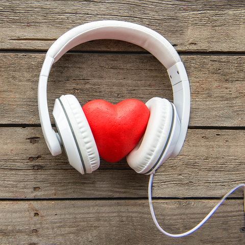 Ein Herz mit Kopfhörer liegt auf einer Holzplatte