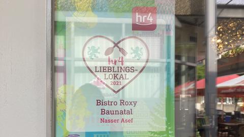 hr4-Lieblingslokal-Plakat im Fenster des "Roxy" in Baunatal